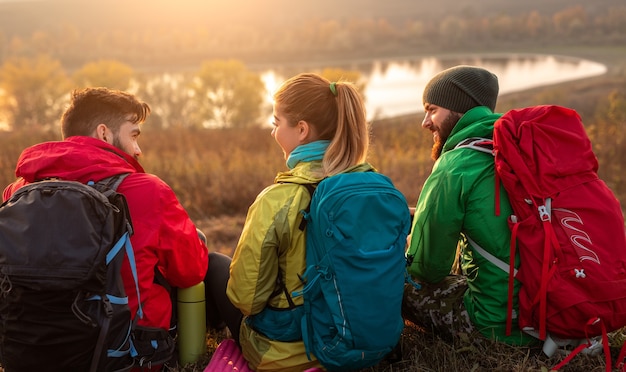 Gruppe von glücklichen Rucksacktouristen, die in der Herbstnatur ruhen