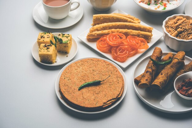 Gruppe von Gujarati-Snacks wie Jalebi-Fafda, Thepla, Khaman Dhokla, Aloo Bhujiya, Khandvi, Khakra, Dahi Vada, Gathiya mit heißem Tee