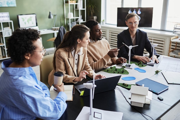 Gruppe von Ingenieuren, die gemeinsam am Tisch ein alternatives Energieprojekt entwickeln, während sie sich im Büro treffen