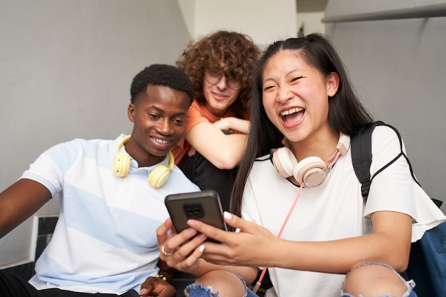 Gruppe von jugendlichen Studenten verschiedener Ethnien, die Handys chinesisches Mädchen mit Kamera verwenden?