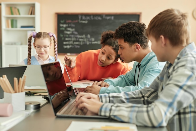 Gruppe von Kindern, die gemeinsam Laptops im Klassenzimmer benutzen