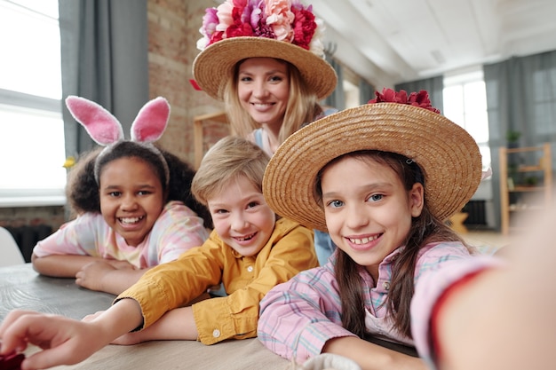 Gruppe von Kindern, die in die Kamera lächeln und zusammen mit ihrem Lehrer ein Selfie-Porträt auf dem Handy machen