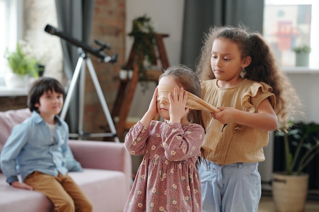 Gruppe von Kindern, die zusammen Verstecken im Zimmer zu Hause spielen