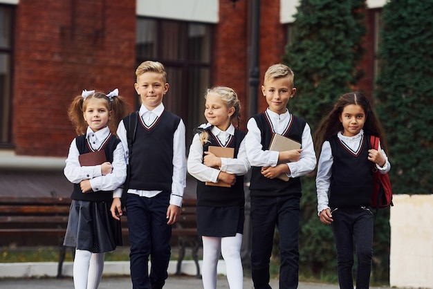 Gruppe von Kindern in Schuluniform, die sich im Freien in der Nähe des Bildungsgebäudes befindet.