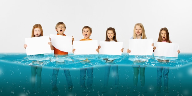 Gruppe von Kindern mit leeren weißen Bannern, die im Wasser des schmelzenden Gletschers stehen, globale Erwärmung