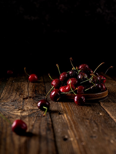 Gruppe von Kirschen auf dunklem Holzhintergrund oder saftige frische Kirschbeeren des Tisches