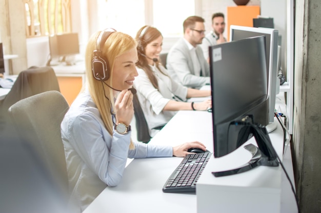 Gruppe von Kundendienstbetreibern, die in einer Reihe im Callcenter-Büro arbeiten