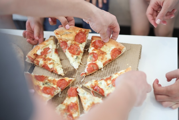 Gruppe von Leuten, die Scheiben der Pizza Nahaufnahme nehmen