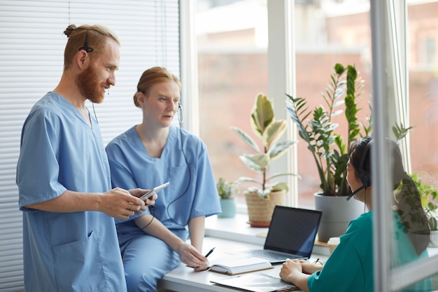 Gruppe von medizinischen Mitarbeitern, die ihre Arbeit im Team besprechen, während sie im medizinischen Callcenter arbeiten