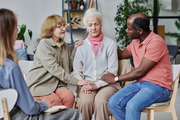 Gruppe von Menschen, die ältere Frauen unterstützen, während sie eine Psychotherapie mit einem Psychologen besuchen