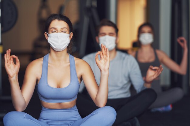 Gruppe von Menschen, die aufgrund von Covid-19 in einem Fitnessstudio mit Masken trainieren