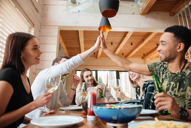 Gruppe von Menschen, die zu Abend essen und High Five geben