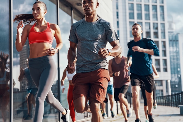 Gruppe von Menschen in Sportkleidung beim Joggen auf dem Bürgersteig im Freien