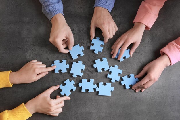 Gruppe von Menschen mit Puzzleteilen auf grauem Hintergrund Einheitskonzept