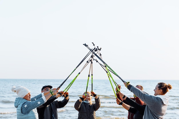 Gruppe von Menschen unterschiedlichen Alters, die skandinavisches Nordic Walking machen, kreuzte Stöcke als Team AG