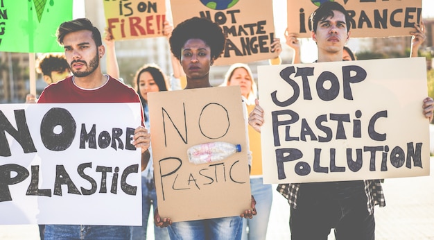 Gruppe von Millennials Demonstranten auf der Straße, junge Menschen aus verschiedenen Kulturen und Rassen kämpfen für Plastikverschmutzung und Klimawandel - Konzept der globalen Erwärmung und Umwelt - Fokus auf Gesichter