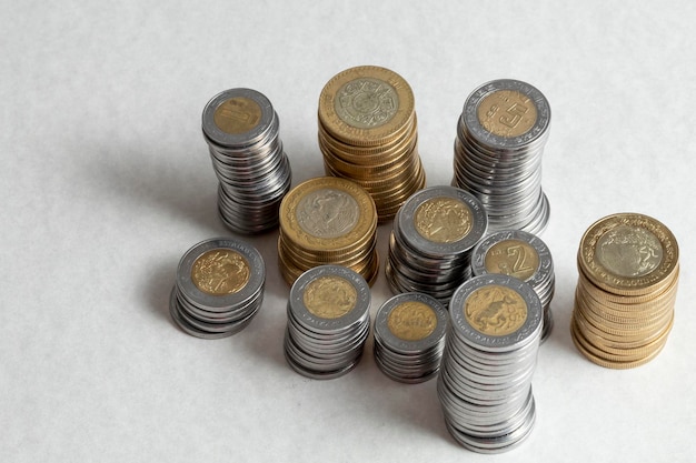 Gruppe von Münzen, die an der Ecke eines Tisches mit Kopierbereich gestapelt sind Mexikanische Pesos