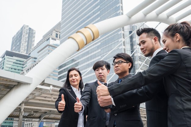 Gruppe von multiethnischen Business-Team zuversichtlich stehen und Daumen hoch in der Stadt zeigen