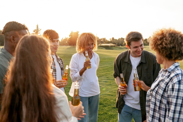 Gruppe von multiracial jungen Leuten, die Bierflaschen in der Hand halten und sich auf einer Outdoor-Party unterhalten