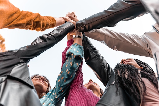 Gruppe von multirassischen Menschen der Jahrtausendgeneration mit ihren Händen im Stapel. Ansicht von unten. Junge Studenten arbeiten am College zusammen. Konzept der Einheit, Vielfalt und Vertrauen