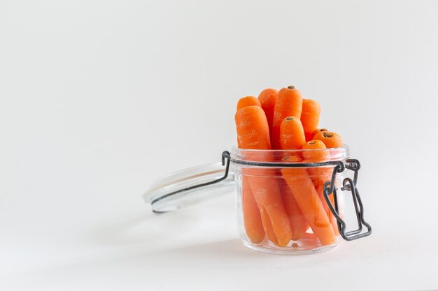 Gruppe von orangefarbenen Karotten in einem Glas-Mason-Glas auf weißem Hintergrund mit Kopierraum veganer Snack