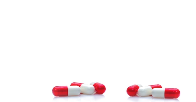 Gruppe von rotweißen Kapselpillen auf horizontalem weißem Hintergrund Verschreibungspflichtige Medikamente Apotheke Drogerie