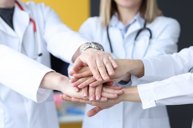 Gruppe von Ärzten, die ihre Hände in der Nahaufnahme der Klinik zusammensetzen. Teamwork im Medizinkonzept