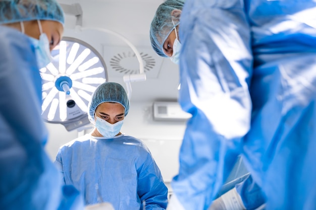 Gruppe von Ärzteteams, die dringend chirurgische Eingriffe durchführen und Patienten im Theater im Krankenhaus helfen Medizinisches Team, das chirurgische Eingriffe in einem hellen, modernen Operationssaal durchführt