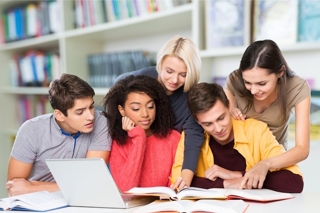 Gruppe von Schülern mit Laptop und Buch, die Unterricht machen