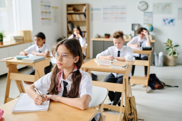 Gruppe von Schulkindern, die während des Unterrichts an Schreibtischen sitzen und in der Schule lernen