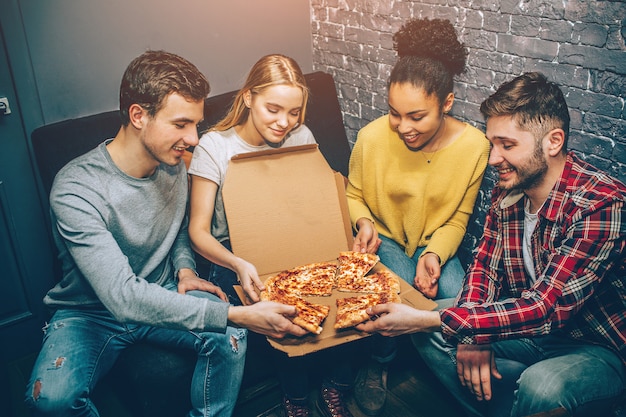 Gruppe von Studenten, die ein Stück Pizza halten