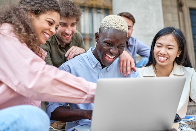 Gruppe von Studenten, die sich ein lustiges Video auf einem Laptop ansehen