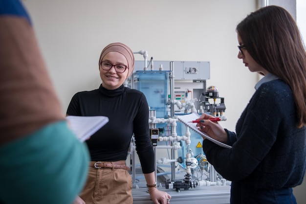 Gruppe von Studenten, die technische Berufspraxis mit jungen muslimischen Lehrerinnen im elektronischen Klassenzimmer, Bildungs- und Technologiekonzept machen