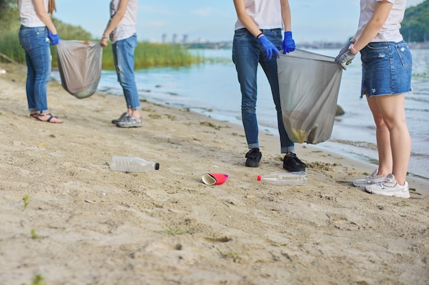 Gruppe von Teenagern am Flussufer, die Plastikmüll in Säcken aufsammeln. Umweltschutz, Jugend, Freiwilligenarbeit, Wohltätigkeit und Ökologiekonzept