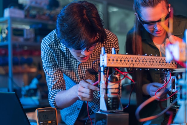 Gruppe von Teenagern, die in einem Labor Experimente zur Robotik durchführen. Jungen und Mädchen in Schutz- und VR-Technik