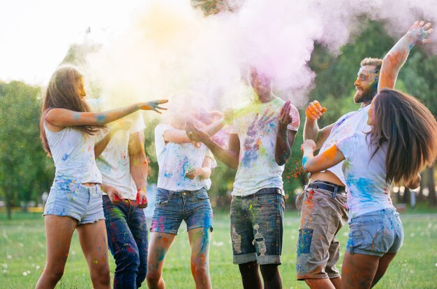 Gruppe von Teenagern, die mit Farben am Holi-Festival in einem Park spielen