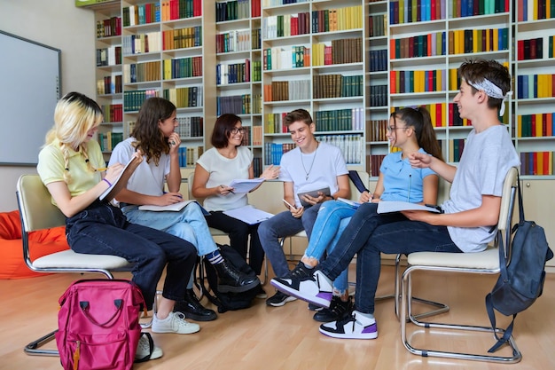 Gruppe von Teenagern mit Lehrerin mittleren Alters in der Bibliothek