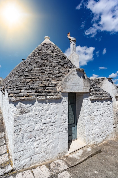 Gruppe von Trulli mit Symbolen, traditionellen alten Häusern und alter Steinmauer in Apulien, Italien