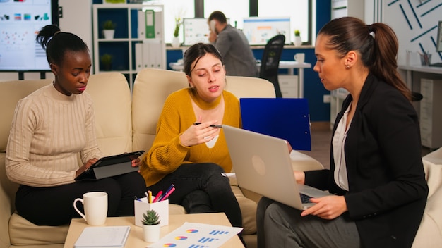 Gruppe von verschiedenen startup-unternehmenskollegen, die sich am professionellen arbeitsplatz treffen, ideen über das management von finanzstrategien austauschen und teilen. glückliche gemischtrassige geschäftsleute, die spaß an der arbeit haben