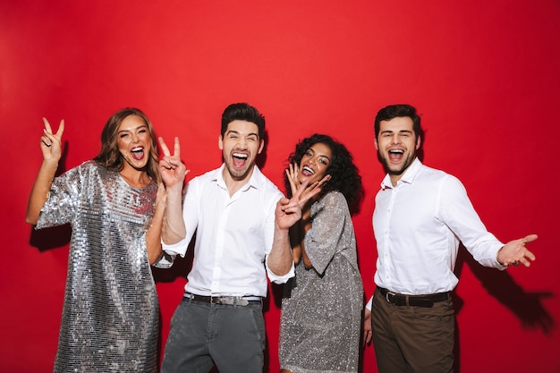 Gruppe von vier fröhlichen, gut gekleideten Freunden, die isoliert über dem roten Raum stehen