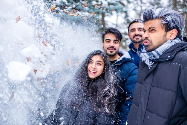 Gruppe von vier Indianern, die Spaß beim Spielen im Schnee im Freien haben und Chrisymas-Feiertage verbringen