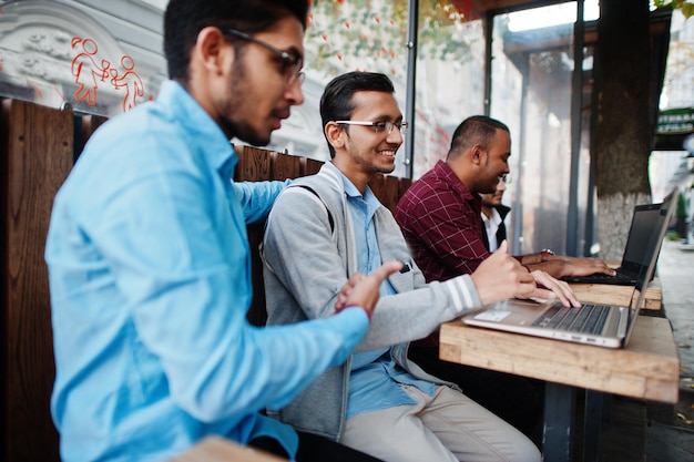 Gruppe von vier indischen jugendlich männlichen Studenten. Klassenkameraden verbringen Zeit miteinander und arbeiten an Laptops.