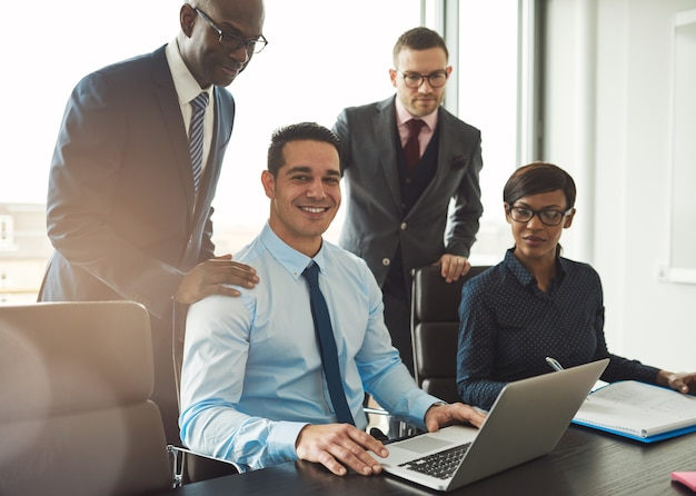 Gruppe von vier schwarzen hispanischen und kaukasischen jungen Geschäftsleuten in einem Meeting in ihrem Büro