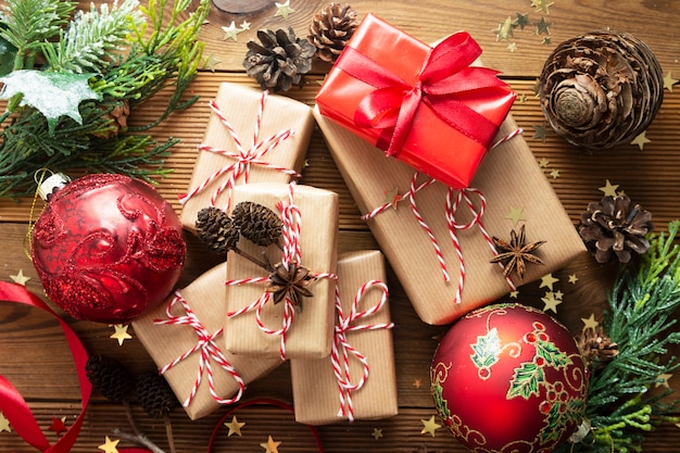 Gruppe Weihnachtsgeschenkboxen eingewickelt im Kraftpapier, Tannenzweige, roter Flitter, Kiefernkegel.