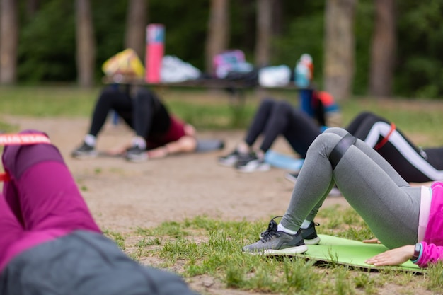 Foto gruppen-stretching-workout - drei süße mädchen strecken sich im freien auf einer grünen wiese im park aus