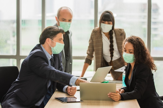 Gruppengeschäftsleute, die sich im Büro treffen, tragen eine medizinische Maske zum Schutz von Covid19 oder Coronavirus