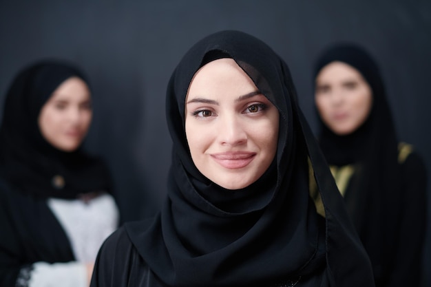 gruppenporträt schöner muslimischer frauen in modischer kleidung mit hijab isoliert auf schwarzem tafelhintergrund, der moderne islammode und ramadan kareem-konzept darstellt