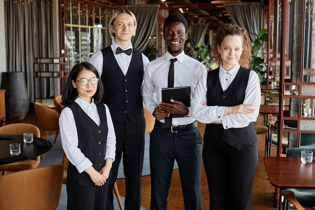 Gruppenporträt von Restaurantmitarbeitern mit Servern, die klassische schwarz-weiße Uniformen tragen und in die Kamera lächeln