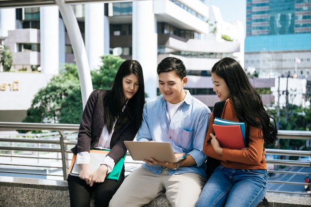 Gruppieren Sie die Studenten, die das Studieren auf dem Laptop studieren, der zusammen sitzt.