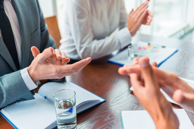 Gruppieren Sie junge Geschäftsleute, die im Büro sitzen und Sitzungen abhalten